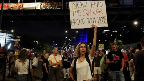 Reuters A demonstrator holds a sign with a reference to Hamas leader Yahya Sinwar, in Tel Aviv