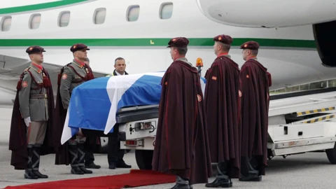 The coffin is loaded onto the plane as soldiers stand guard